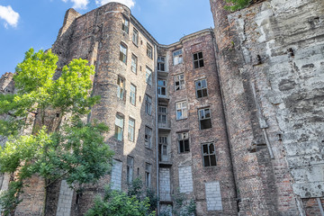 Facade of ruined old vintage red brick house with broken windows (location: Kamienico, part of...