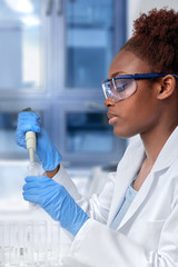 African-american scientist or graduate student in lab coat loading samples with pilette