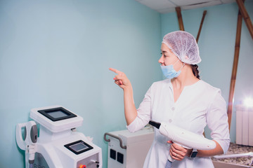 specialist keeps hand piece for hair removal in the hands for cosmetic procedure