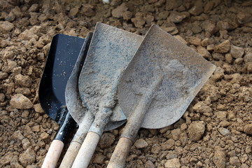 New and heavily used dirty shovels on construction site