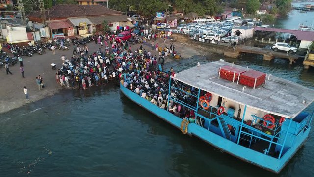 A lot of people come out from the ferry to the shore. People expect landing on a small ferry. Aerial view.