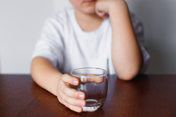 A boy holding an empty glass and waits.