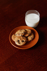 A glass of fresh milk and oatmeal cookies on a wooden table.