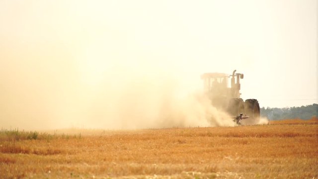 A tractor with a plow plows the field after harvesting. Slow motion