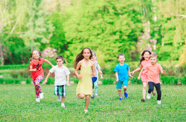 Many different kids, boys and girls running in the park on sunny summer day in casual clothes