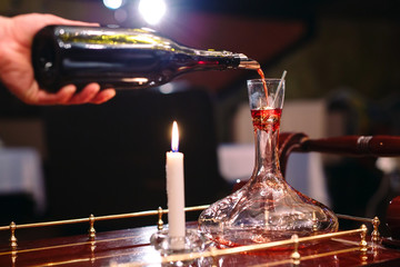 A sommelier pouring red wine into decanter