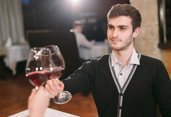 Beautiful young couple with glasses of red wine in luxury restaurant