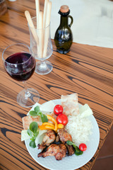 dark red wine with bread sticks and chicken legs with a Mediterranean salad