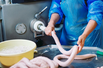 Butchers processing sausages at meat factory.