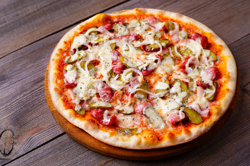 Delicious napoli pizza with salami and gherkins on wood, close up. Italian food, restaurant menu photo
