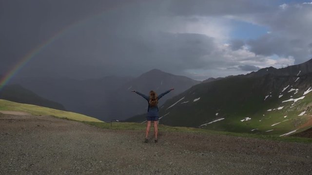 Happy traveler girl raises her hands up shows the rainbow Colorado Mountains