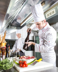 The chef prepares a dish in the kitchen of restoran.