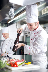 The chef prepares a dish in the kitchen of restoran.