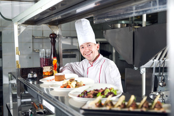 Portrait of a chef with cooked food in the Kitchen in the restaurant.