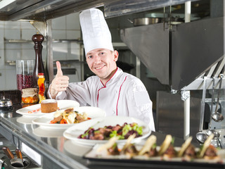 Portrait of a chef with cooked food in the Kitchen in the restaurant.