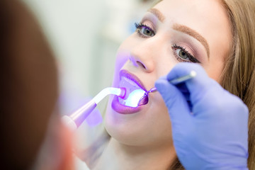 Dentist doing procedure with dental curing UV light in clinic