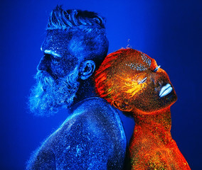 Concept. Portrait of a bearded man and woman painted in ultraviolet powder.