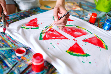 Drawing on clothes. Girl draws on a white T-shirt.