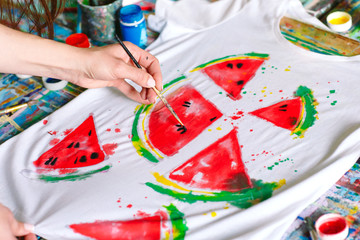 Drawing on clothes. Girl draws on a white T-shirt.