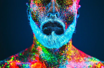Concept. Portrait of a bearded man. The man is painted in ultraviolet powder.