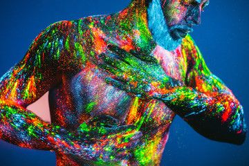 Concept. Portrait of a bearded man. The man is painted in ultraviolet powder.