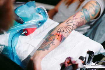 Professional tattoo artist makes a tattoo on a young girl's hand.