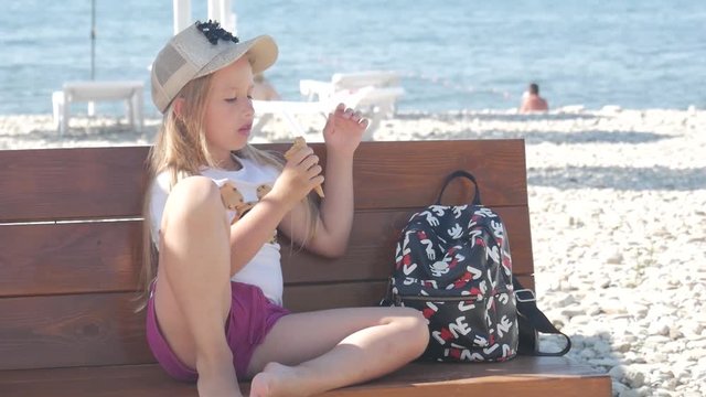 Teenage girl on summer holidays, talking sitting on seaside bench with ice cream. Child eating ice cream on beach.