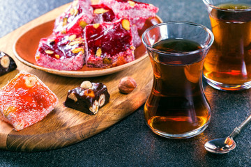 Two glass of Turkish tea and rahat lokum, hazelnuts on stone grey surface.Traditional Turkish...
