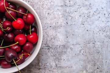 White bowl of cherries on granite background with room for text