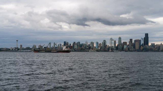 UHD 4k time lapse movie of moving clouds and sky over urban scenic view of downtown city skyline Seattle Washington and Elliott Bay in Puget Sound from Alki Beach ultra high definition