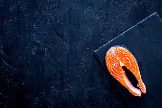 Raw Salmon Steak On Cutting Board On Black Background Top View Copy Space