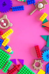 Developing children games frame. Colorful plastic bricks and blocks on pink background top view space for text