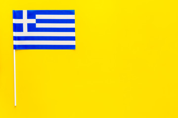 Fototapeta premium Greece flag concept. small flag on yellow background top view copy space