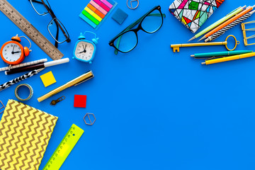 Education concept. Stationery for school pupil mockup with glasses and notebook on blue background top view copy space