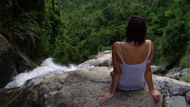 A woman sits on top of a waterfall