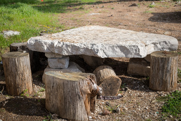 Small table made of tree trunks and a stone plate