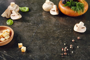 White Champignon Mushrooms on Dark Stone Plate Background with Dill, Basil, Pepper and Croutons