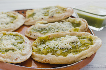 Mexican sopes with grated cheese and green salsa, mexican food spicy in mexico