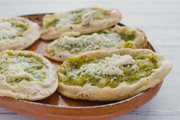 Mexican sopes with grated cheese and green salsa, mexican food spicy in mexico