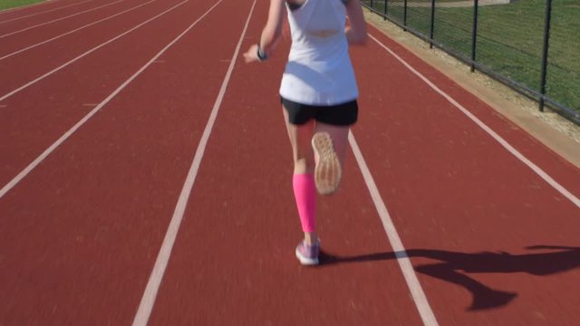 Teen Girl Athlete Runs On A Track With Camera Following Behind Her