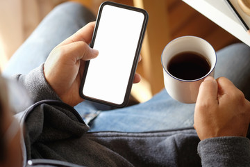 Cropped shot of an unrecognizable man touching smartphone screen at desk in office.