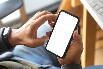 Cropped shot of an unrecognizable man touching smartphone screen at desk in office.