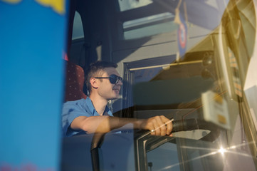 Young man at the wheel is looking away from the bus