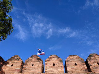 thailand flag on brick wall in front of blue sky