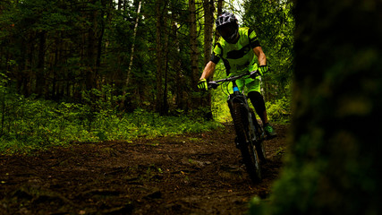 in the green uniform of a cyclist riding through the woods with mountains in the helmet