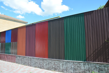 Stacks of various colorful metal fence panels and metal roof sheets for sale.