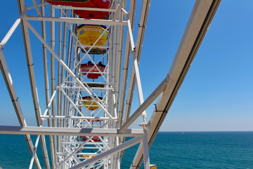 Close upward view of a colorful ferris wheel with blue sky background