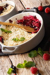 English healthy dessert: berry crumble with currant berries, raspberries and blueberries decorated with mint closeup. vertical