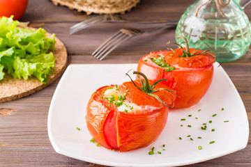 Fresh tomatoes baked with cheese and chicken egg on a plate on a wooden table