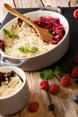Berry crumble with currants, raspberries and blueberries decorated with mint close up. vertical